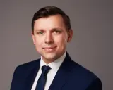 Portret mężczyzny w granatowym garniturze i białej koszuli z krawatem.