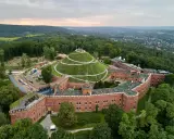 Widok z lotu ptaka na Kopiec Kościuszki otoczony ceglanymi fortami i otulony zielenią.