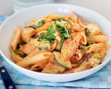 En skål med krämig penne med kyckling och zucchini, toppad med salladslök. En riktigt god pasta!