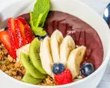 Acai-Schüssel mit Früchten, Granola und einem Hauch von Vitamin C. Erdbeeren, Bananen, Kiwi, Blaubeeren und Himbeeren machen diese Schüssel zu einem gesunden Genuss.