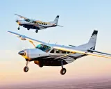 Zwei Cessna Grand Caravan Flugzeuge fliegen im Sonnenuntergang.