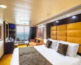 Interno di una cabina con balcone MSC Splendida: letto king-size, divano arancione, TV e vista mare.