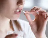 Kobieta bierze tabletkę clindamycin mip 600, trzymając szklankę wody.