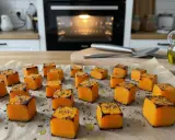 Dés cubes de courge rôtis sur une plaque de cuisson, prêts pour une délicieuse recette de courge au four. L'huile d'olive et les herbes ajoutent une touche savoureuse.