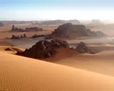Sanddünen und Felsformationen in der algerischen Kulturlandschaft der Sahara. Ein Ort, der Geschichten von Nomaden und alten Zivilisationen erzählt.