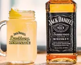 En iskallad Jack Daniel's Lynchburg Lemonade i ett glas med handtag, bredvid en flaska Jack Daniel's Tennessee Whiskey.