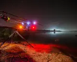 Nocne łowienie karpi. Wędki na podpórce z sygnalizatorami brań, jezioro i gwiazdy. To jak zrobić świetlik na ryby.
