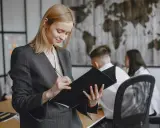 Kobieta w garniturze analizuje dokumenty, przygotowując się do ważnego spotkania. Jej zaangażowanie świadczy o profesjonalnym podejściu do stosunku pracy.