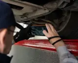 Mechanik robi zdjęcie podwozia auta, by sprawdzić numer VIN.