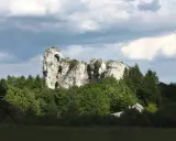 Imponujący okiennik wielki, skalna brama wśród zieleni, z ukrytą chatką.