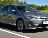 Szara Toyota Corolla E16 jedzie po drodze, za kierownicą siedzi mężczyzna.