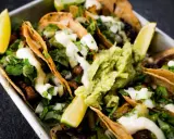 Saftige Tacos al Pastor mit Guacamole, Koriander und Limettenspalten.