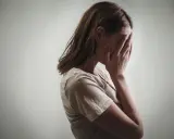 Kobieta zakrywa twarz dłońmi, co może symbolizować różne psychozy objawy, takie jak przytłoczenie czy izolacja.