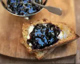 Ein Toast mit Butter und ausgefallener Heidelbeermarmelade, die in einem silbernen Schälchen daneben serviert wird.