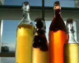 Cztery butelki z napojem, w tym jedna z ciemnymi owocami. To domowa kombucha co to jest? Napój fermentowany, zdrowy i pyszny.