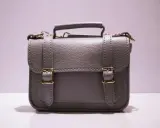 Graue Handtasche mit goldenen Schnallen und Griff. Perfekt, um Ihre wichtigsten Dinge zu handtasche organisieren.
