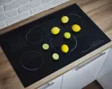 Nowa płyta indukcyjna w rogu kuchni, ozdobiona cytrynami i limonkami, czeka na kulinarną przygodę.