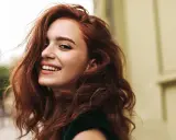 Donna con capelli rossi mossi e un sorriso radioso. La sua chioma è così bella che si può fare la tinta ogni 15 giorni per mantenerla perfetta.
