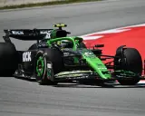 Ein grüner Formel 1 Bolide mit KICK-Sponsorenaufdruck rast auf der Rennstrecke. Die leistungsstarken Formel 1 Motoren lassen ihn über den Asphalt fliegen.