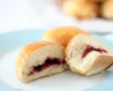 Dos bollos dorados, uno cortado, revelan un relleno de mermelada de fresa. ¡Un dulce bocado!