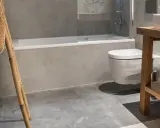 Baño moderno con ducha y WC suspendido. El suelo de microcemento y paredes grises dan un toque minimalista. Ideal para calcular el precio reforma baño 4 m2.