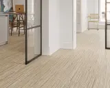 Un moderno revestimiento del suelo de madera clara con un diseño lineal crea un ambiente acogedor en un interior luminoso.