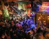 Menschen tanzen und feiern in einem belebten Club in Lissabon. Grüne Pflanzen und Lichter schaffen eine lebendige Atmosphäre.