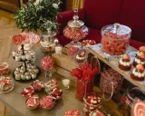 Un candy bar boda casero lleno de dulces rojos y rosas, piruletas, pasteles y golosinas.
