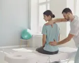 Fizjoterapeuta bada plecy pacjentki. W takich sytuacjach, gdy choroba uniemożliwia pracę, można starać się o świadczenia, np. komu przysługuje renta chorobowa.