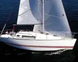 Voilier blanc à voiles gonflées, naviguant sur l'eau sombre. Les avis sur le Sun Fast 32 confirment sa rapidité.