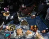 Familie feiert Fastenbrechen im Islam mit Picknick im Freien. Kekse, Früchte und Kaffee werden geteilt.