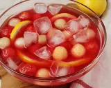 Erfrischende melonenbowle ohne alkohol mit Eiswürfeln, Melonenbällchen und Zitronenscheiben in einer Glasschüssel.