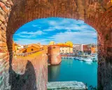 Widok na port w Livorno przez ceglany łuk. Widać łodzie, budynki i fortyfikacje. Idealne miejsce, by zobaczyć Livorno.