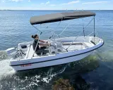 Ce bateau Terhi 450, propulsé par un moteur Honda de 6 cv, navigue sur une mer calme. Idéal pour explorer les côtes.