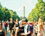 A couple kisses at a pride parade in Germany, with the Victory Column in the background. This scene shows Germany is gay friendly.