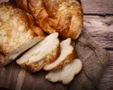 Puszyste ciasto drożdżowe, pokrojone w kromki, na drewnianej desce. Dowiedz się, jak przechowywać ciasto drożdżowe, by było świeże.