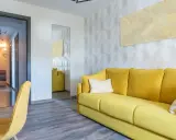 Un sofá amarillo vibrante y un sillón a juego llenan la habitación, destacando los alegres colores de sofás.