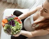 Kobieta w ciąży delektuje się zdrową sałatką, dbając o dietę w ciąży. Kolorowe warzywa to podstawa.