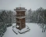 Drewniana wieża widokowa na Mazurach w zimowej scenerii. Otoczona ośnieżonym lasem, zaprasza do podziwiania krajobrazu.