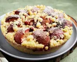 Ein köstlicher pflaumenkuchen ohne hefeteig, bestreut mit Puderzucker und knusprigen Streuseln.