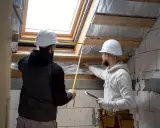 Dos trabajadores miden un tragaluz para mejorar la eficiencia energética.
