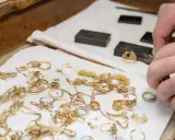 Mani esperte valutano gioielli d'oro, anelli e collane, un modo pratico per imparare come riconoscere l'oro.