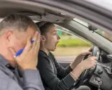 Instructor desesperado mientras una joven conductora, con cara de sorpresa, intenta sacarse el carnet de coche.