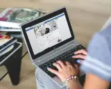 Kobieta pisze na laptopie, przeglądając stronę z inspiracjami wnętrzarskimi. To świetny post powitalny przykład dla nowych użytkowników.