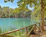 La albufera de Anna, con su agua turquesa y rodeada de árboles frondosos, invita a un paseo tranquilo. Patos nadan en la superficie.
