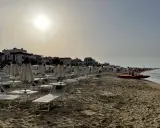 Spiaggia di Igea Marina con lettini e ombrelloni chiusi, bagnino pronto con la sua imbarcazione sul mare calmo.