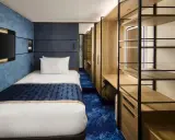 Interno cabina singola nave da crociera: letto, TV a parete, armadio aperto con mensole e scrivania. Le dimensioni delle cabine sono ottimizzate per il comfort.