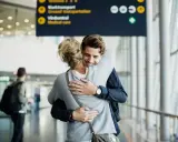 Glädjefylld återförening på en av Sveriges internationella flygplatser. Ett par kramas varmt i terminalen.