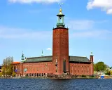 Stockholms stadshus reser sig stolt vid vattnet, dess ikoniska torn dominerar horisonten.
