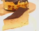 Kawałek puszystego keto sernika z mascarpone, polany czekoladą. Cały sernik w tle.
